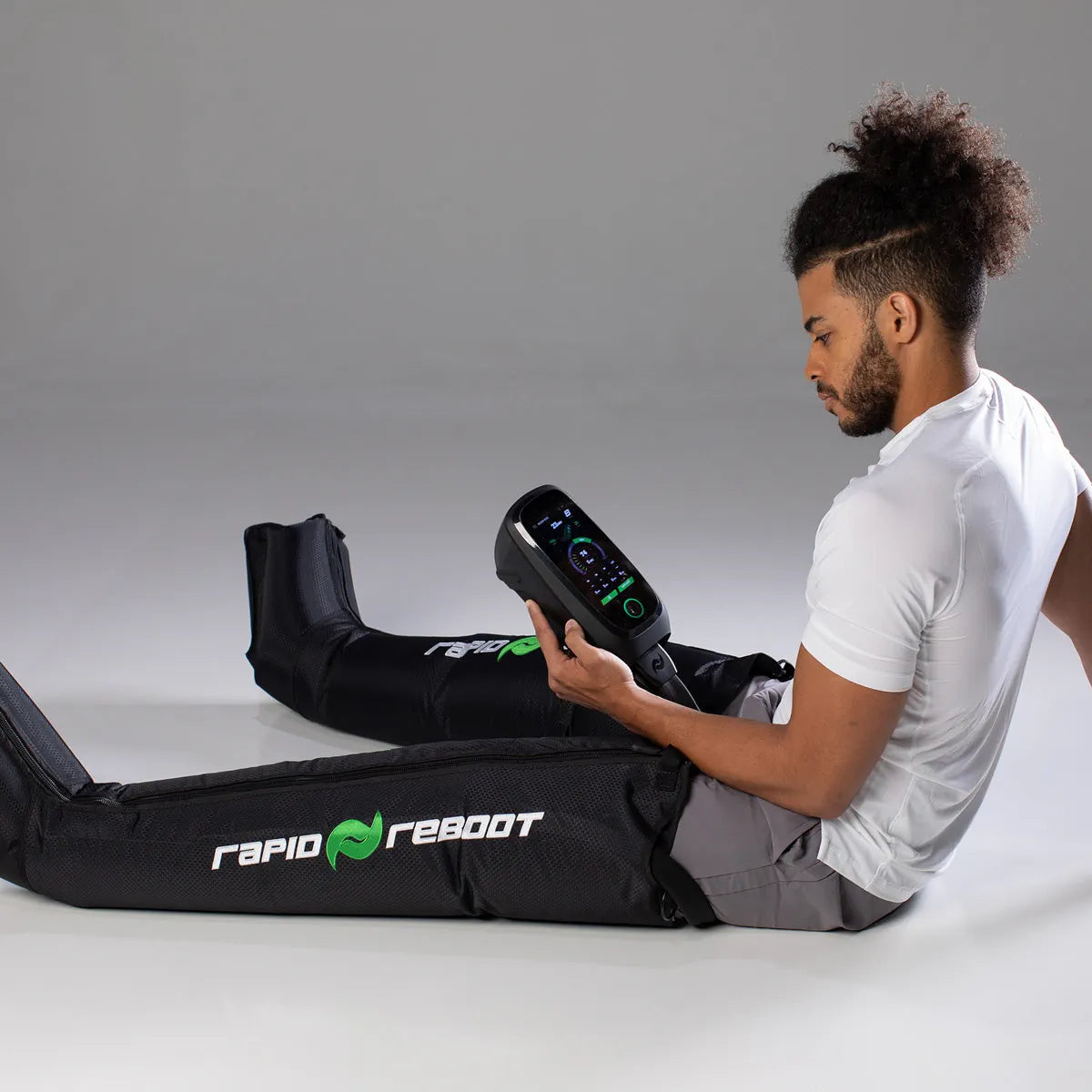 Athlete adjusting the Rapid Reboot REGEN control unit while wearing the boots