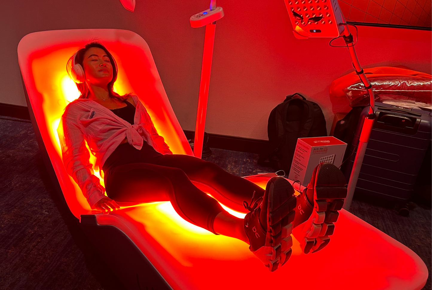 User reclining on the EnergyLounger in a dim treatment room illuminated with deep red light.