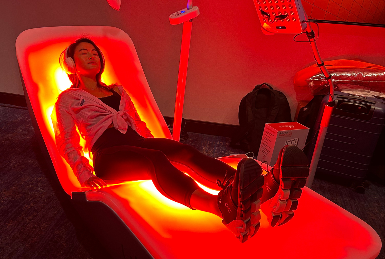 User reclining on the EnergyLounger in a dim treatment room illuminated with deep red light.