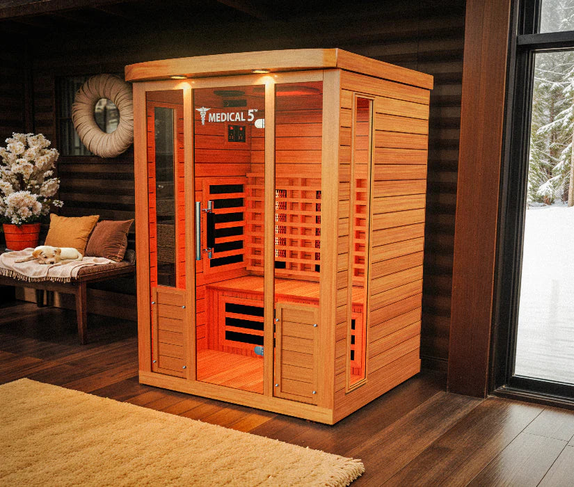 Wooden infrared sauna in a room with a window showing a snowy landscape.