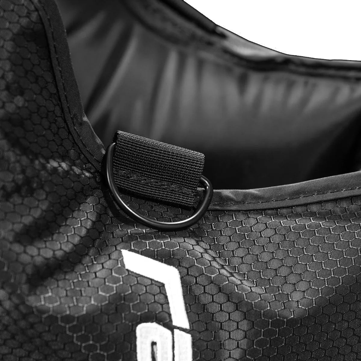 Close-up of a black bag with a D-ring and hexagonal pattern