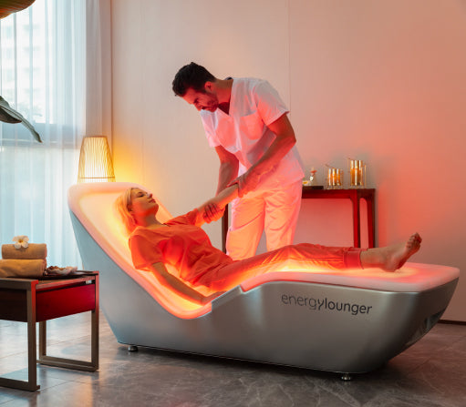 Therapist helping a client start a session on the EnergyLounger full-body therapy lounger.