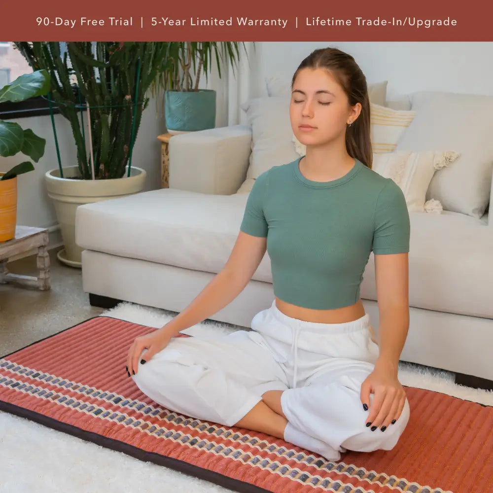 Woman meditating on a full-size HealthyLine TAO mat in a living room.