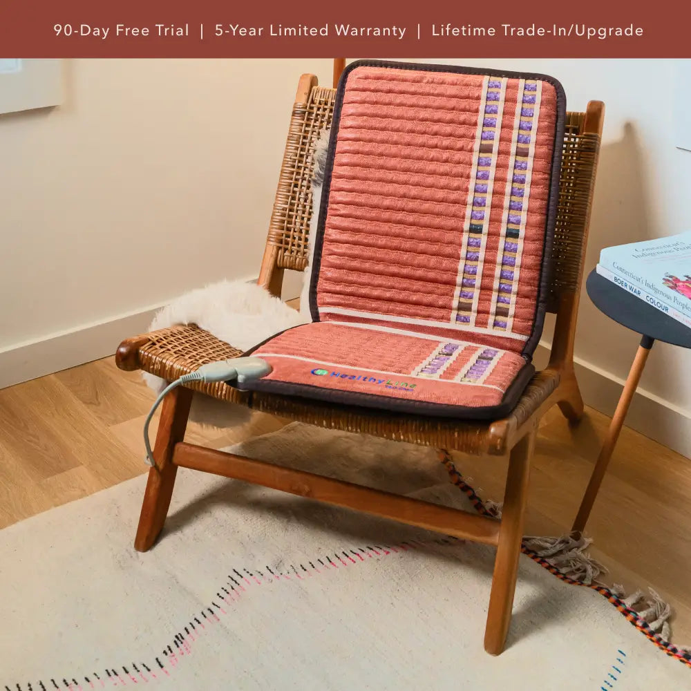 “HealthyLine TAO 40×18 chair mat placed on a woven wooden chair in a living room, showing the gemstone channels and attached controller.”