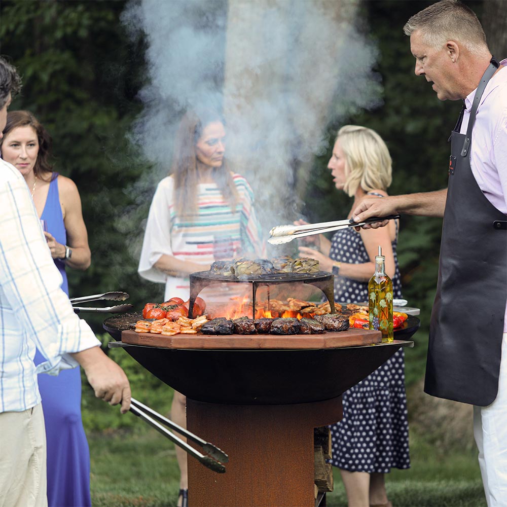 Group of people grilling together on an Arteflame 40-inch grill during an outdoor gathering.