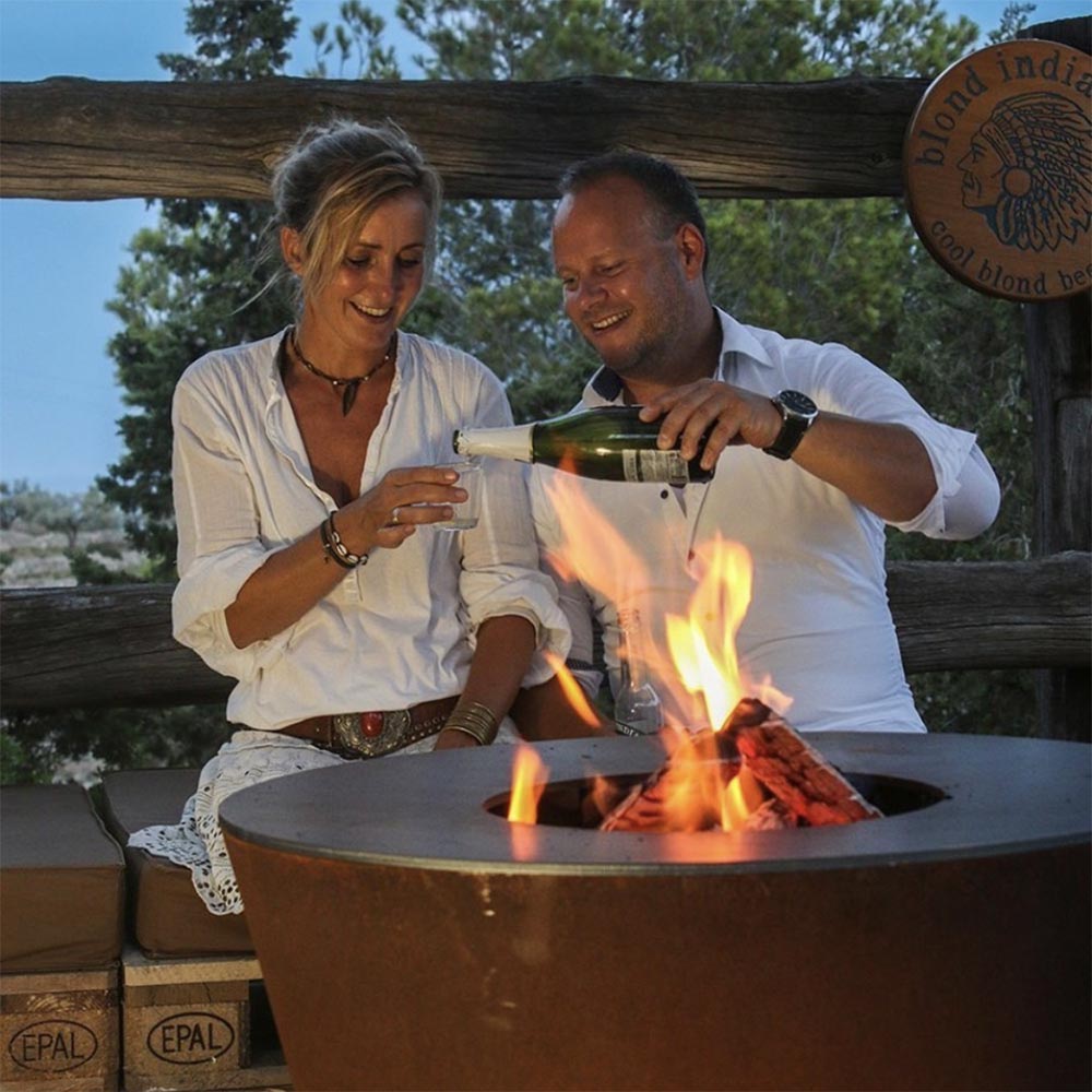 Couple gathered around the Arteflame grill being used as a fire bowl during the evening.