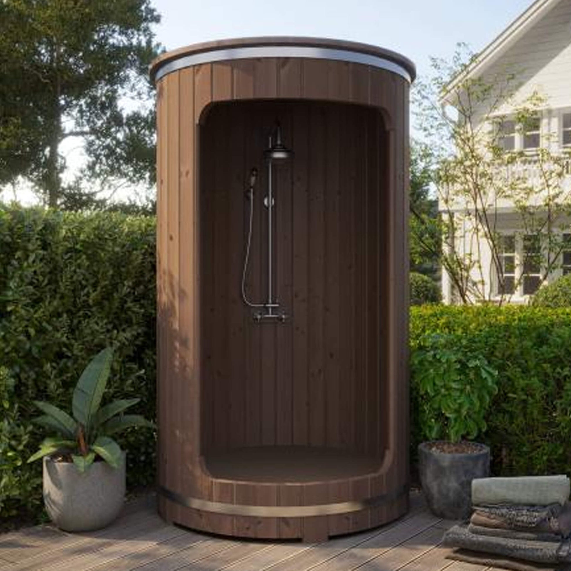 SaunaLife Model R3 Barrel Shower installed outdoors in a landscaped backyard, showing full thermo spruce exterior and chrome shower fixture.