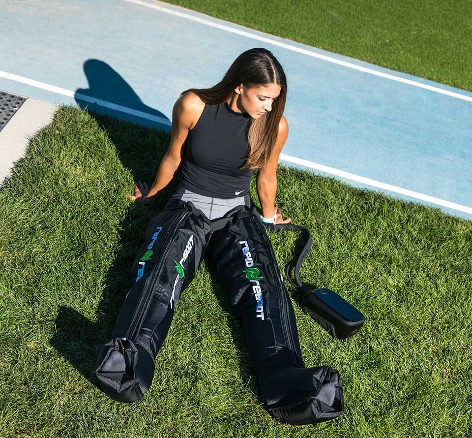 Athlete using Rapid Reboot REGEN compression boots outdoors during recovery.